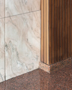 Parete in doghe di legno verticali affiancata ad un rivestimento in marmo sia a parete che a pavimento